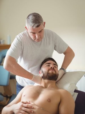 Physiotherapist examining neck of a patient in clinic